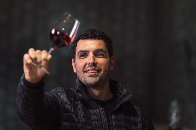 Man tasting red wine in a winery barrel cellar