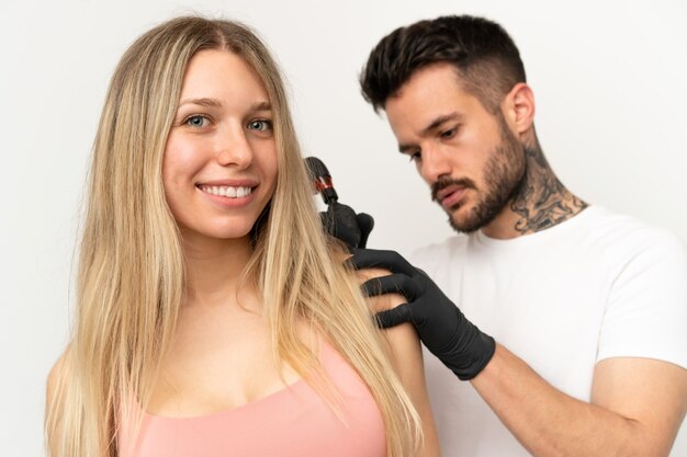 Man tattooing a girl over isolated background