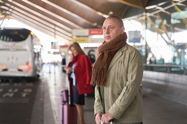 Man te wachten bij het busstation man van middelbare leeftijd te wachten op een taxi op de luchthaven