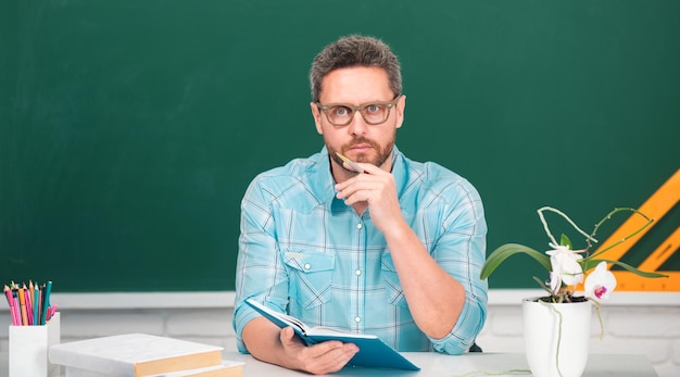 Man teacher with books and chalkboard professor on lesson at college teachers day