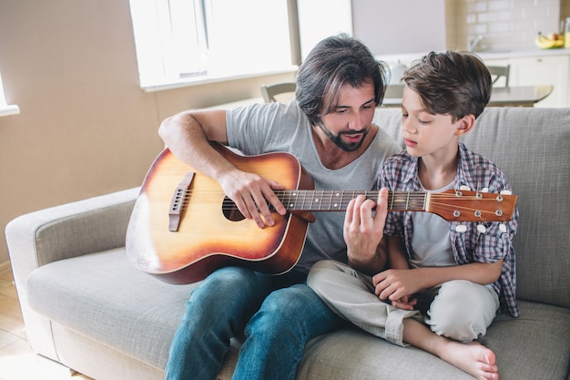 Man teaching his son how to play on the guitar