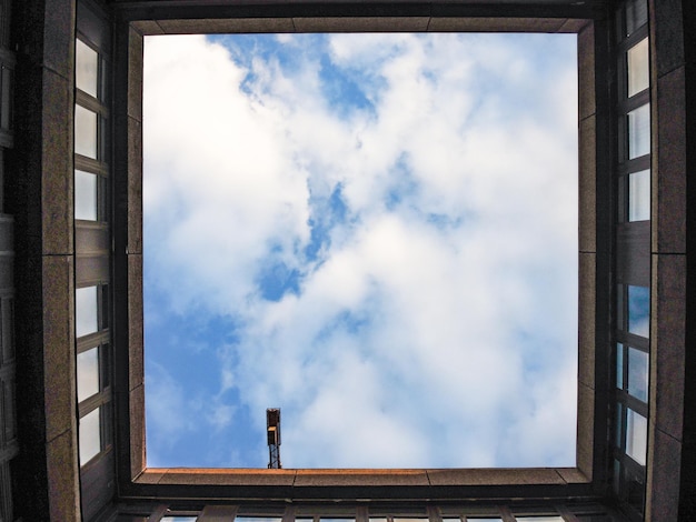 Man tegen bewolkte lucht gezien door het raam