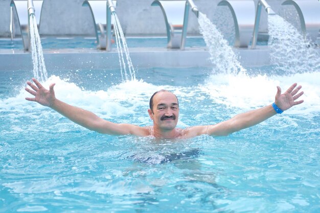 Photo man in thermal pool with hydromassage and  injectors with water jets