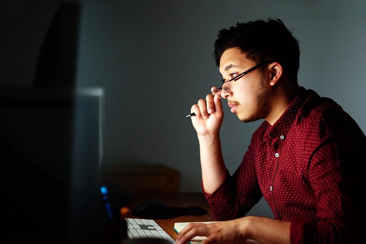 Photo man thinking and computer at night in office with notebook coding information or software programming geek developer pc and notes with glasses for database update it report and server deadline