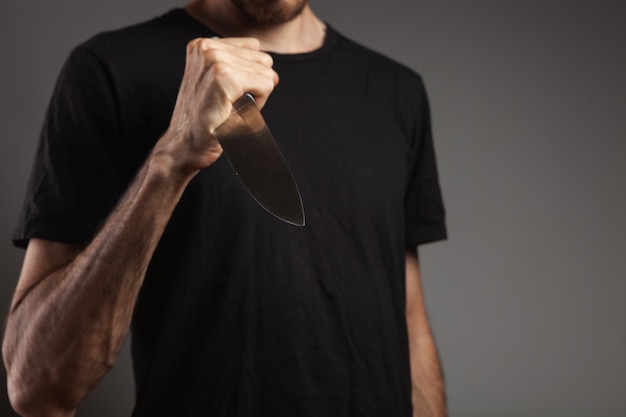 Man threatens with a knife on gray background