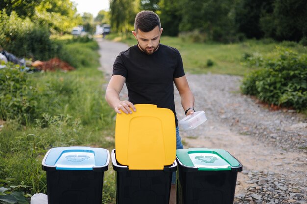 Photo man throwing out in recycling bin clean empty plastic container different colour of recycling bins