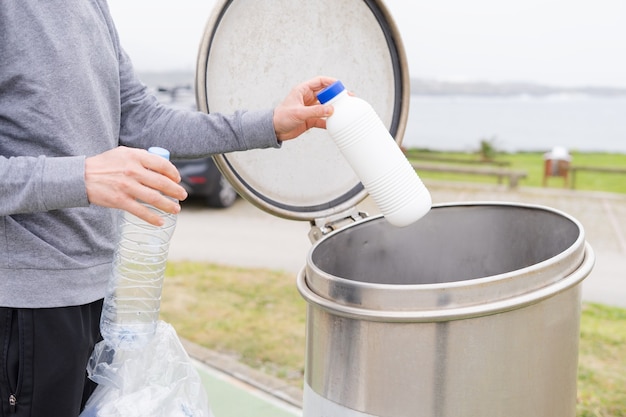 プラスチック リサイクル ポイントでプラスチック容器を投げる男。