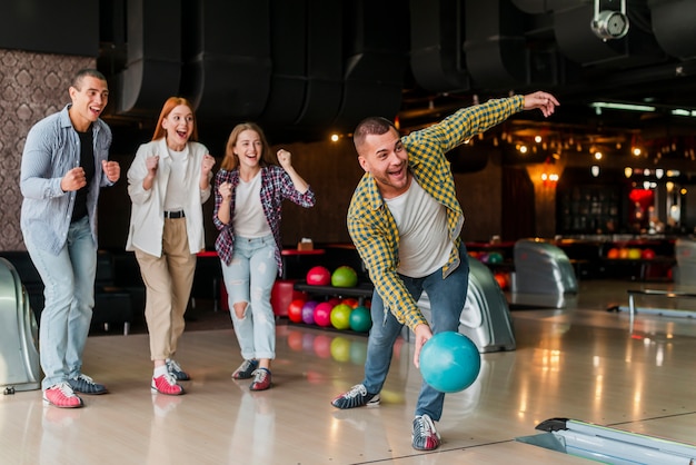 Photo man throwing a turquoise bowling ball