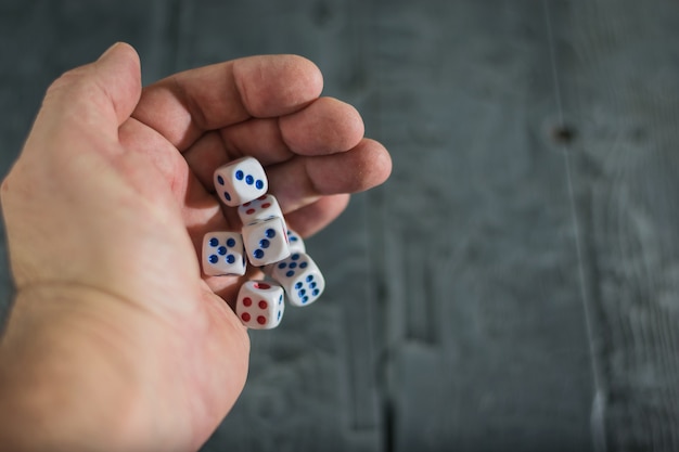 A man throws dice on wood table.