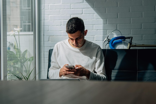 Man thuis aan het werken of studeren met mobiele telefoon en computer