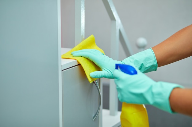 man thuis tafeloppervlak schoonmaken met handdoek en handschoenen, desinfecterende spuitfles. het doorbreken van genderstereotypen, sekseneutraal.