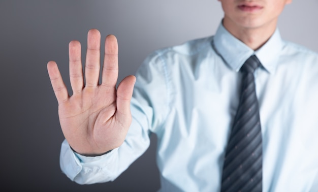 Man in tie shows stop on gray surface