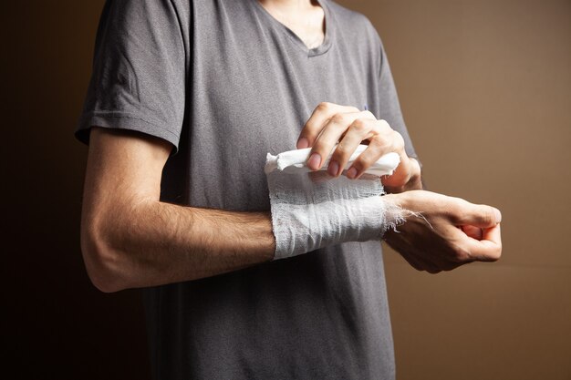 Man tied his hand with a bandage on a brown background