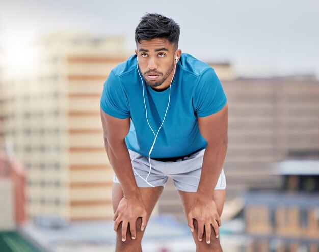 写真 男は疲れて、街で運動トレーニングや背景をぼかした写真の建物や呼吸によるトレーニングのために走っています