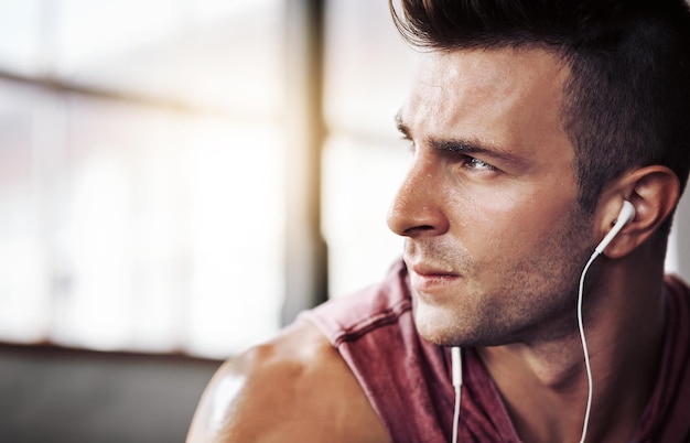 man tired and music in gym for training workout and wellness with radio for motivation exercise thinking and male bodybuilder on break from cardio fitness and earphones for listening to podcast