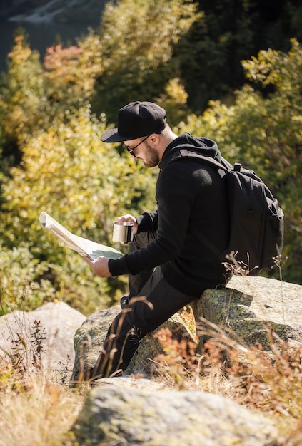 Man toeristische ontspannen op de top van een heuvel, kijken naar een prachtig landschap van bergen en meer.