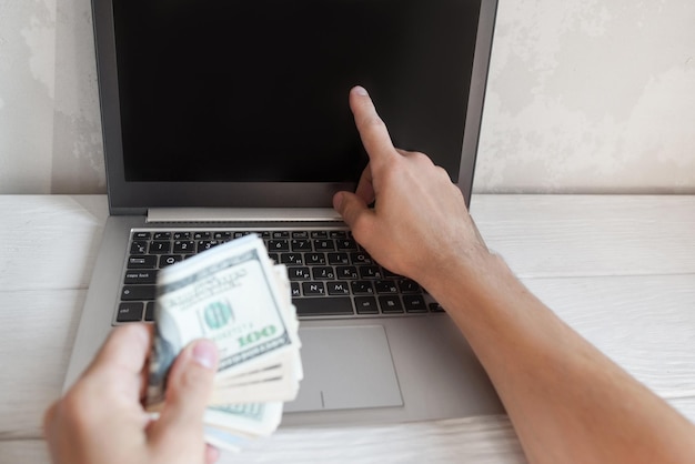 Man toont iets op laptopscherm met geld