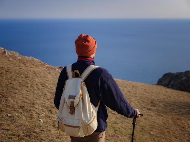 日没時に春の山々の崖の上に立ち、自然の景色を楽しむ男性