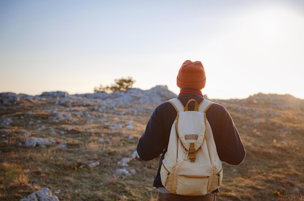 A man on top of a cliff in the spring mountains at sunset and enjoying the view of nature