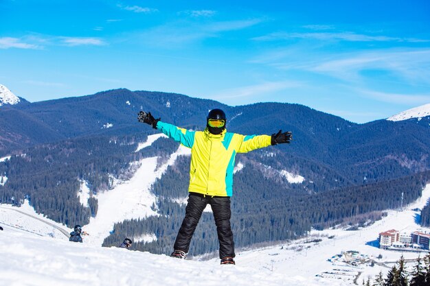 晴れた日にスノーボードで丘の頂上にいる男。冬の山