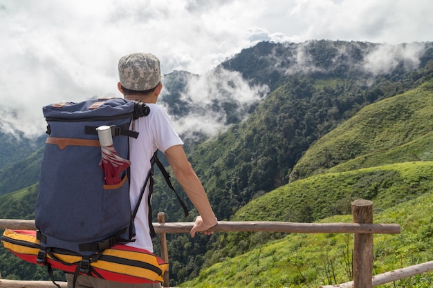 山の上に立っている男は、山の景色を見ている岩の上に立っています。