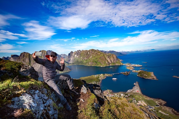 ノルウェーのロフォーテン諸島の島々で自分撮りをしている山の頂上にいる男。