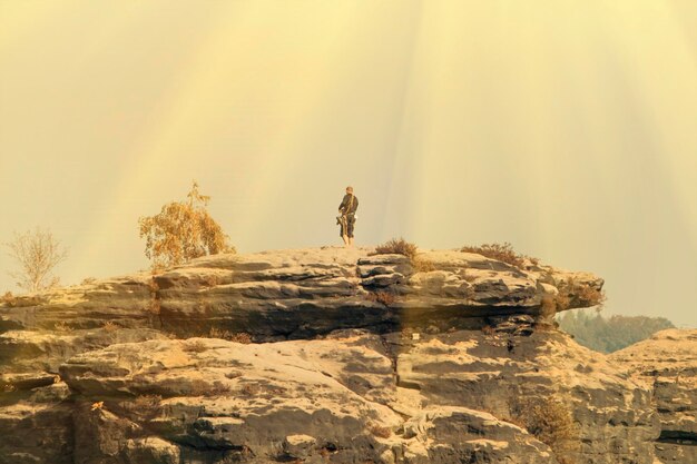 The man on top of a rock against the sky