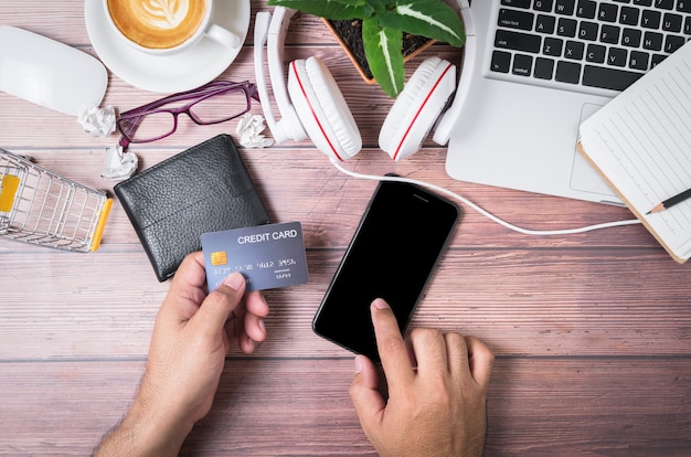 Foto equipaggi il tocco sul telefono cellulare dello schermo nero e la tenuta della carta di credito sul portafoglio