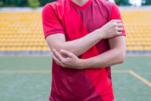 Man touching arm standing on stadium