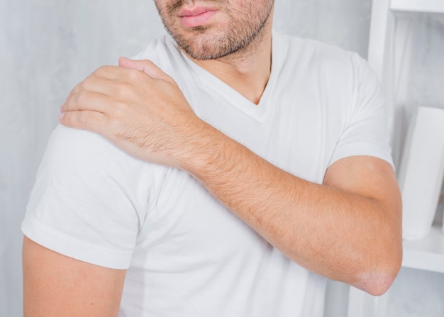 Foto un uomo che tocca la sua spalla ferita con la mano