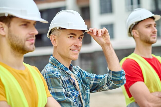 Foto uomo che tocca il casco protettivo con la mano e i lavoratori