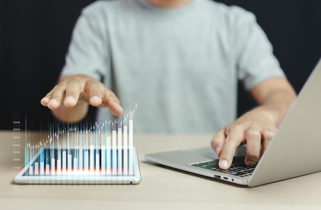 Man touching tablet screen with trading graph using laptop. stock exchange marketing analyzing chart. information statistics diagram profit. investment and marketing concept.