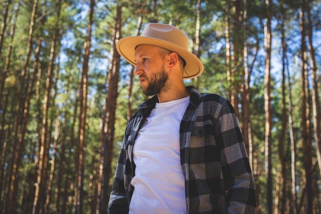 Man tourist in hat and plaid shirt in the woods