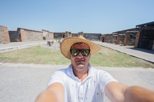 Man tourist in hat and sunglasses making selfie at Pompeii ancient city Italy