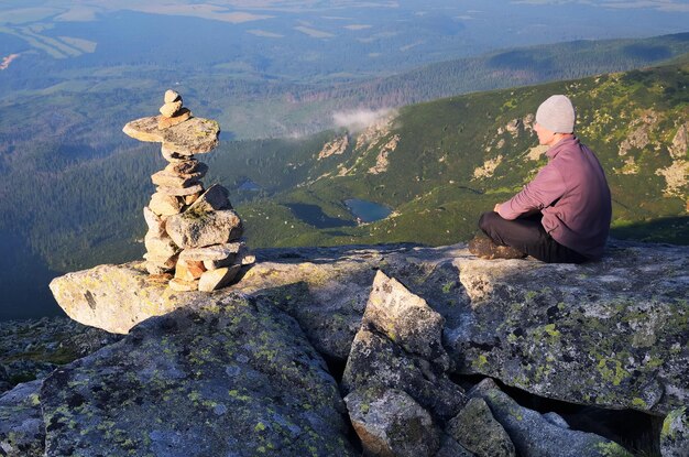 Man tourist is sitting on top of a mountain