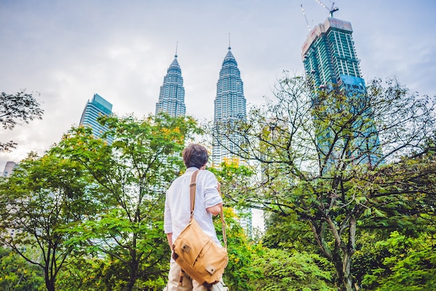 Photo man tourist in malaysia looks at the petronas twin towers