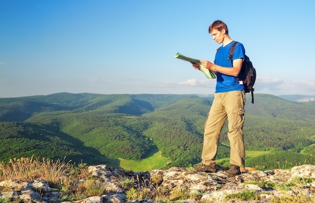 Турист человек в горе читал карту. Человек на вершине горы. Концепция туризма