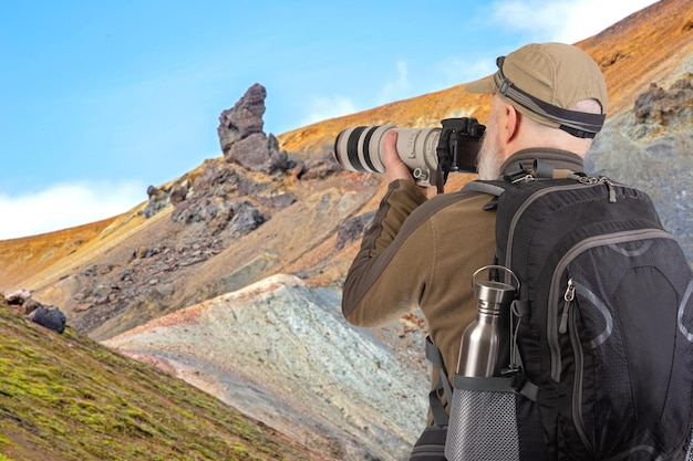 バックパックを背負った男性の観光写真家が自然の美しさを撮影しています