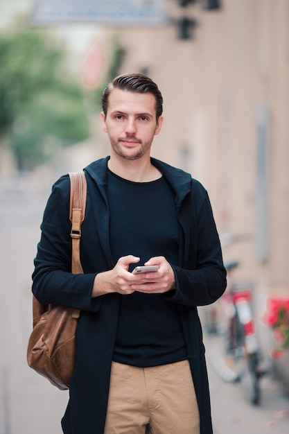 Equipaggi il turista con una mappa della città e lo zaino in via dell'europa. ragazzo caucasico che guarda con la mappa della città europea.