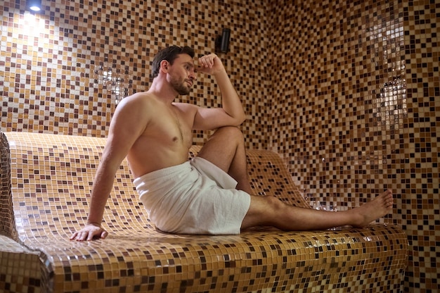 A man in a towel sitting in sauna and having detox session