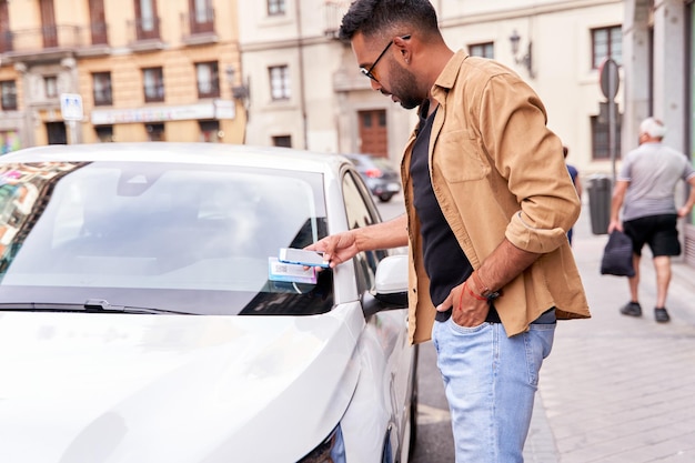Мужчина в городе арендует общий автомобиль через мобильное приложение, сканируя qr-код