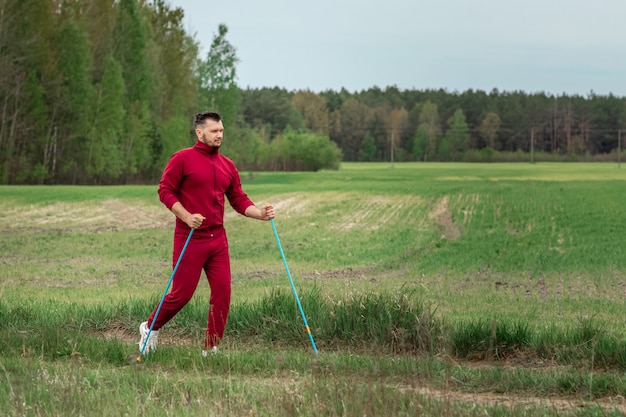 トラックスーツを着た男性がノルディックウォーキングをしている