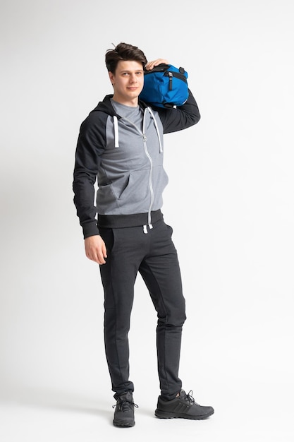 Мужчина в спортивной футболке и кроссовках с тренировочной сумкой в руках