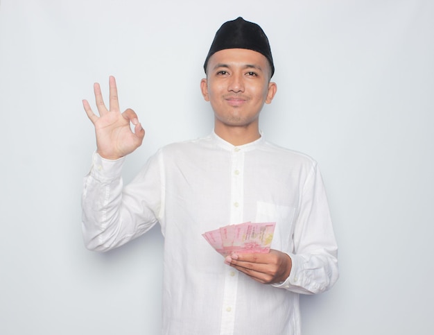 A man in a traditional dress holds a stack of money in his hand and says'happy new year'on the top.