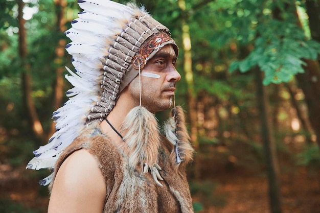 A man in traditional Native American clothing in the evening forest