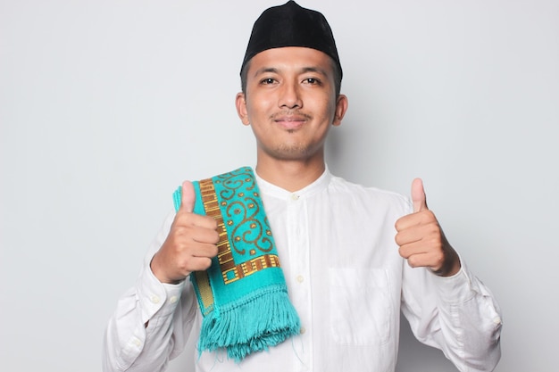 A man in a traditional outfit with a blue scarf and a thumbs up sign.