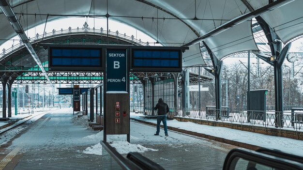 Foto uomo sulla piattaforma della stazione ferroviaria in inverno