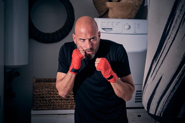 Man training boxing in the laundry room at home with a bag and gloves