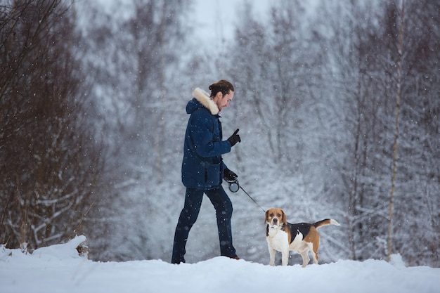 Photo man training dog beagle in winter. snowing day
