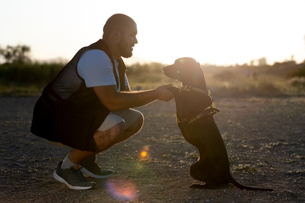 Man training his dog outdoors at sunset